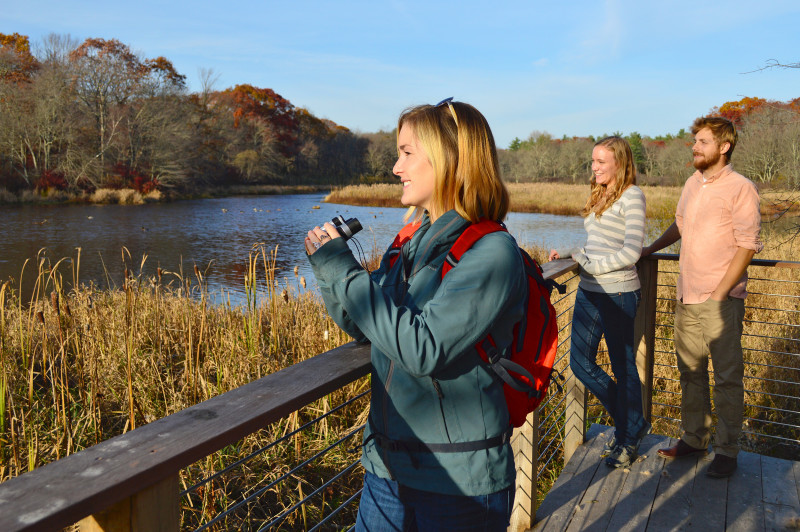 three people looking out over the Acushnet River from The Sawmill