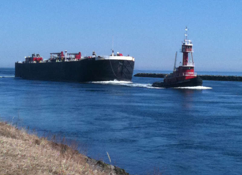 a tug towing a barge into Cape Cod Canal