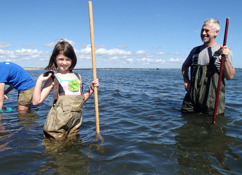 girl standing in water at Fort Taber holding up a quahog