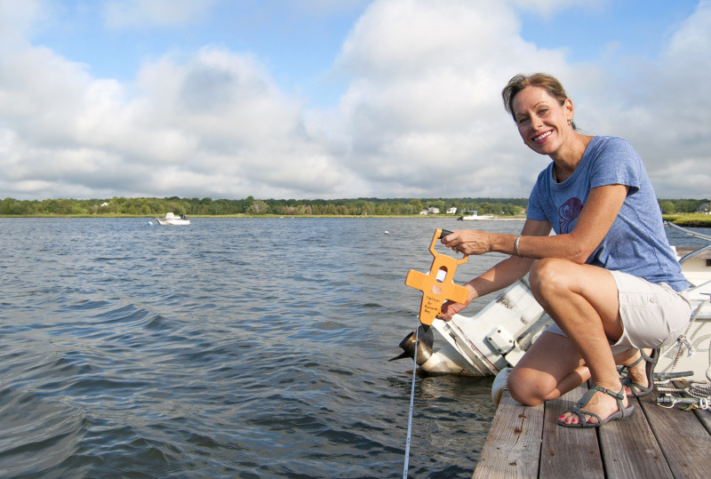 a woman holding a Secchi disc by the water in Dartmouth