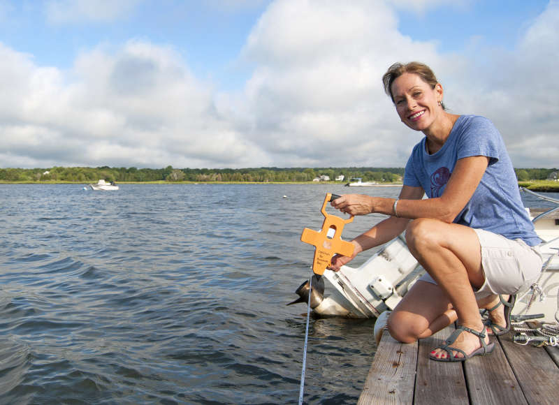 a woman holding a Secchi disc by the water in Dartmouth