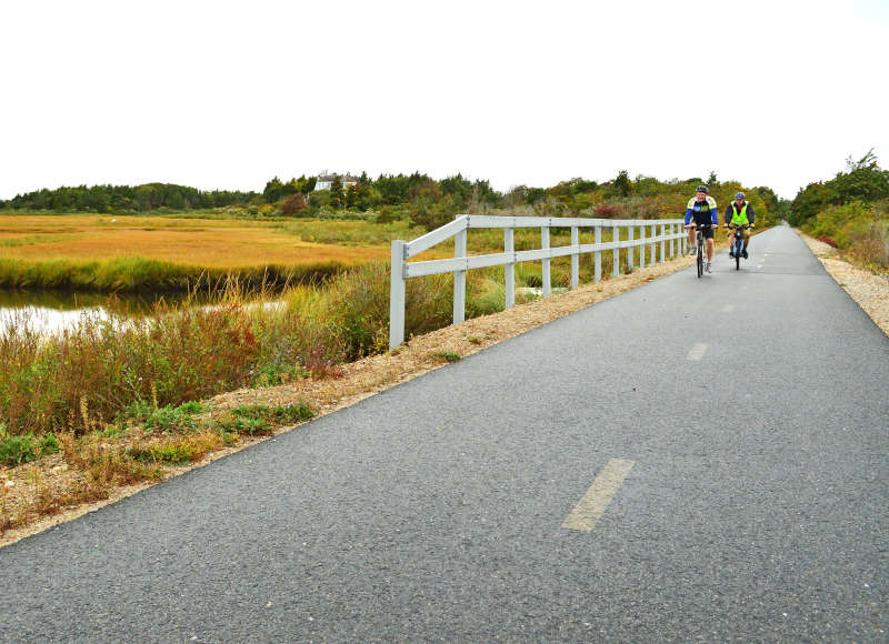 two cyclists riding on Shining Sea Bikeway in autumn