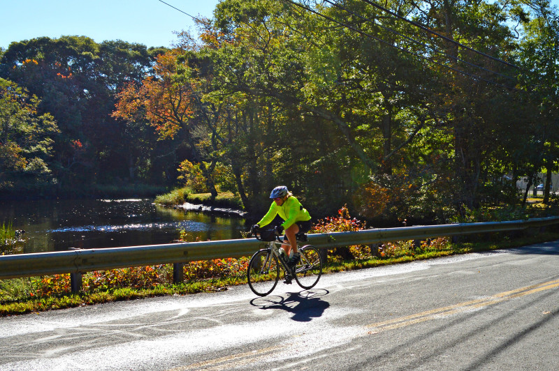 a woman bikes past the Paskamansett River