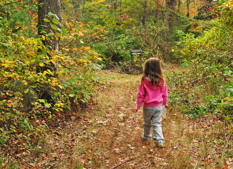 young girl walking down a trail through the woods