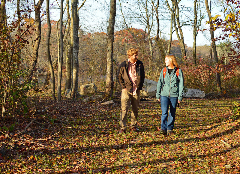 two people walking on a trail through the woods at The Sawmill in Acushnet