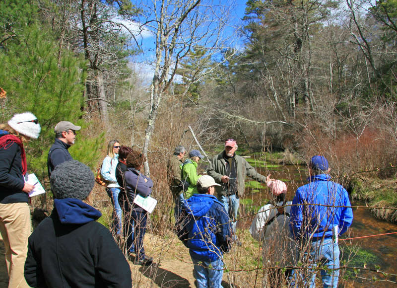 people gathered around a stream during a Buzzards Bay Coalition Decision Makers Workshop