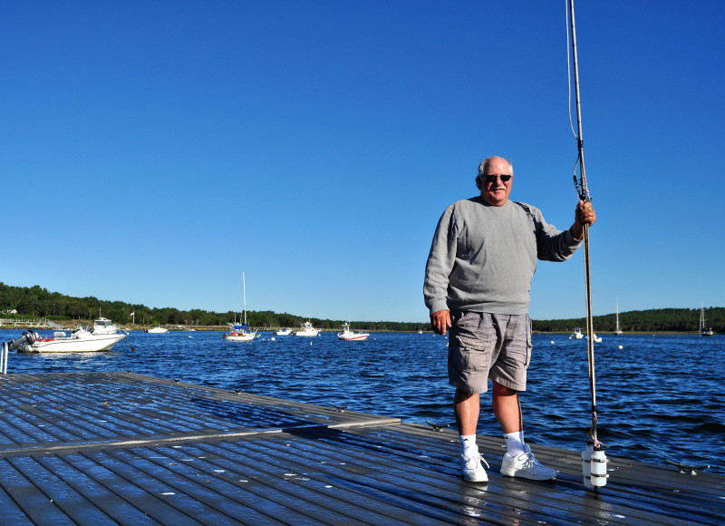 a Baywatcher volunteer holding a sampling pole on a dock on Wings Cove in Marion