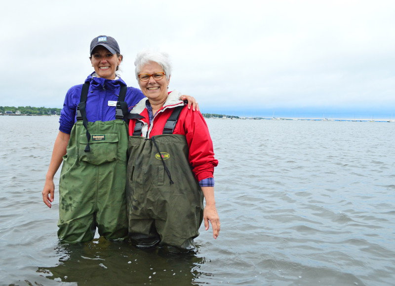a mother and daughter stand in Mattapoisett Harbor wearing waders