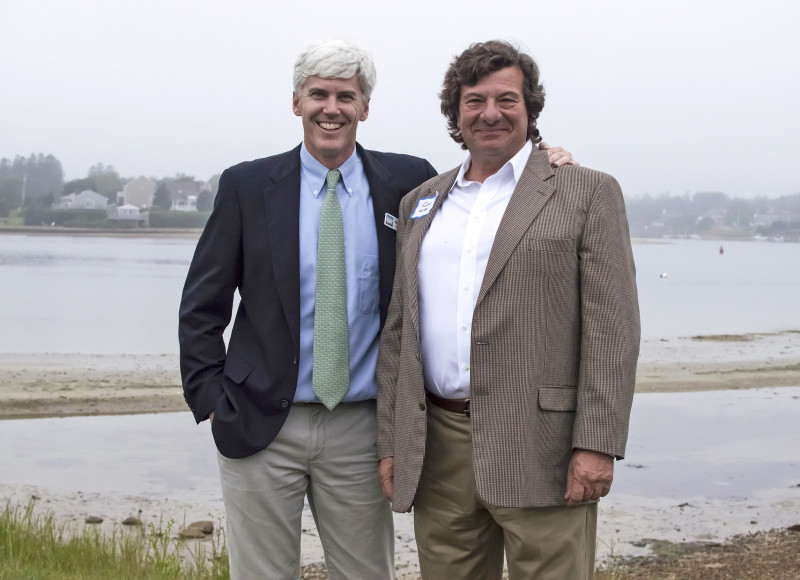 two men in suits standing next to Buzzards Bay in Bourne