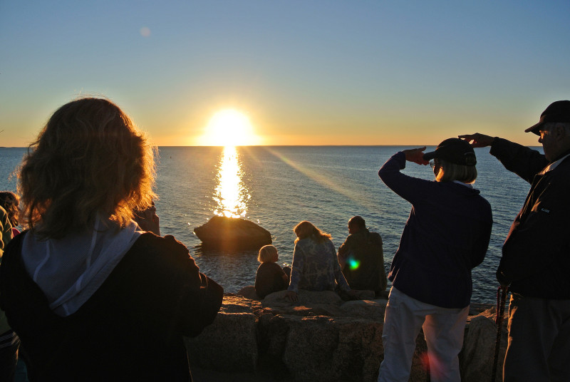 a group of people watching the sunset over Buzzards Bay from The Knob in Falmouth