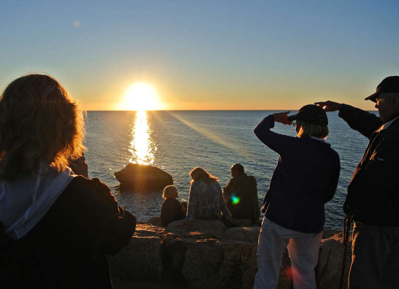 a group of people watching the sunset over Buzzards Bay from The Knob in Falmouth