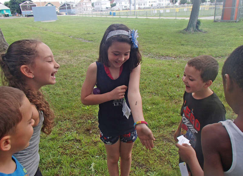 a caterpillar crawls up the arm of a laughing girl