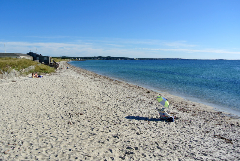 people sitting in the sand on a sunny day at Chapoquoit Beach in Falmouth