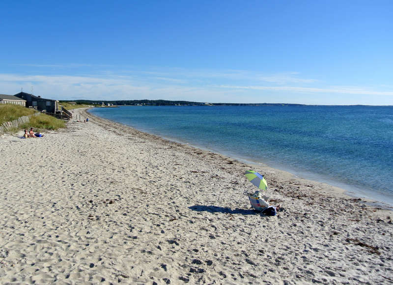 people sitting in the sand on a sunny day at Chapoquoit Beach in Falmouth