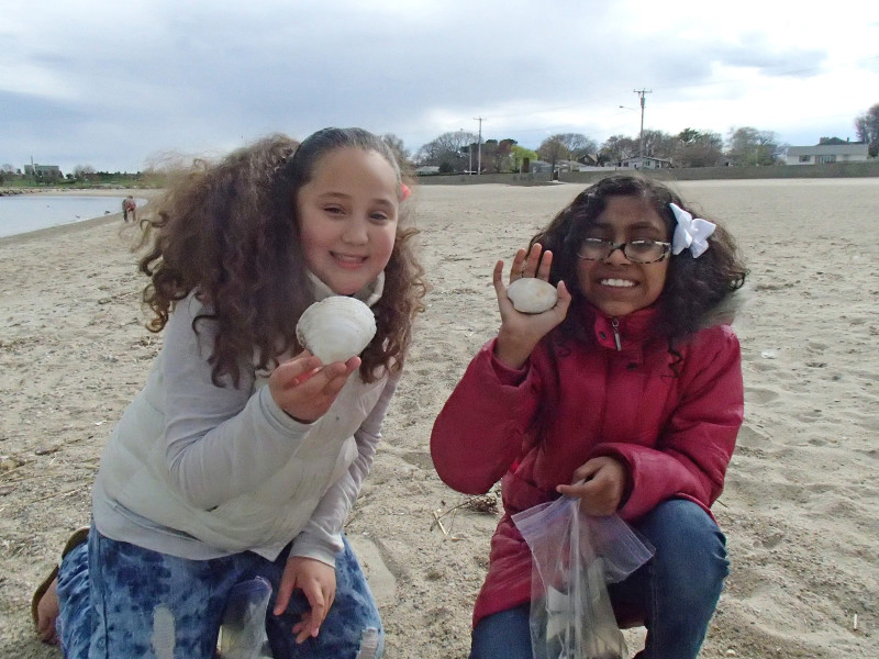 two girls hold up clam shells at East Beach in New Bedford