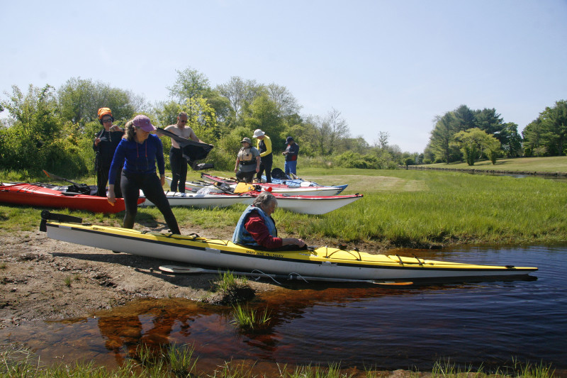 a man launches a kayak into the East Branch of the Westport River from the Head of Westport Town Landing