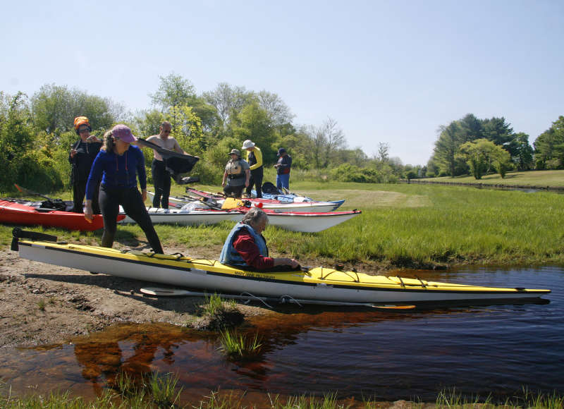 a man launches a kayak into the East Branch of the Westport River from the Head of Westport Town Landing