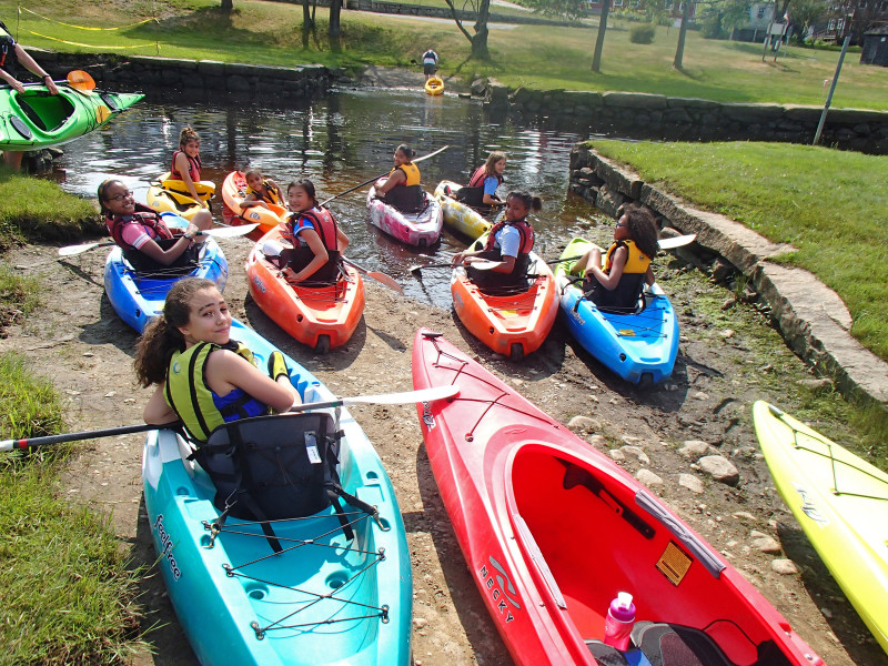 a group of girls launch kayaks into the East Branch of the Westport River from the Head of Westport Town Landing