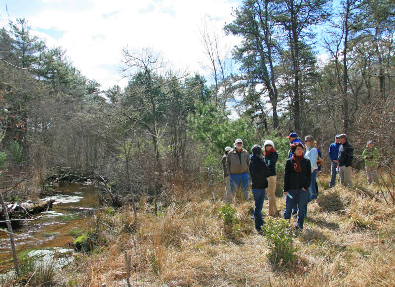 a group of people walking past Red Brook at the Lyman Reserve in Plymouth