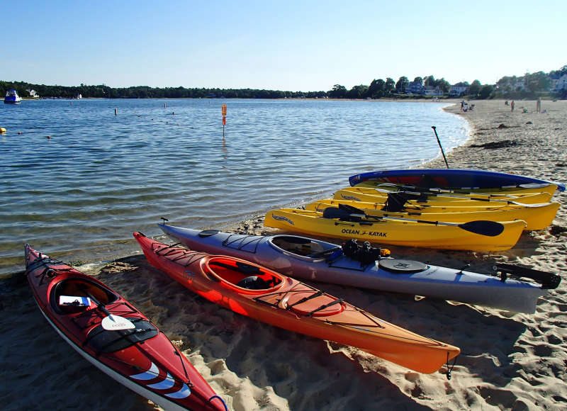 several kayaks lined up in the sand at Onset Beach
