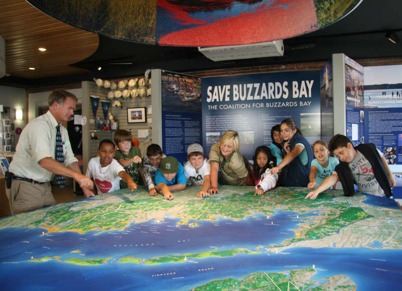a group of kids gathered around a large map of Buzzards Bay