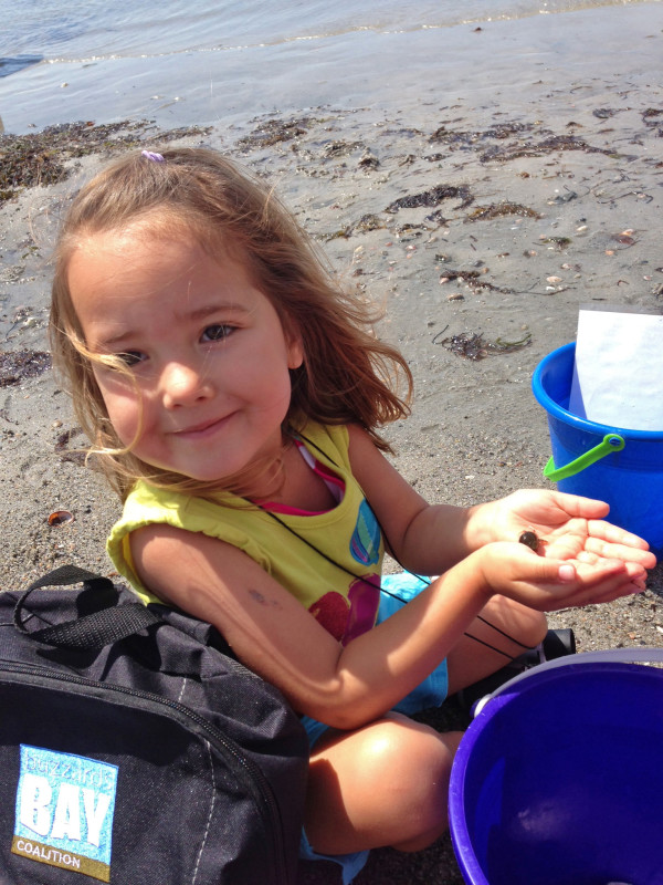 young girl on West Island beach with hermit crab and beach pails