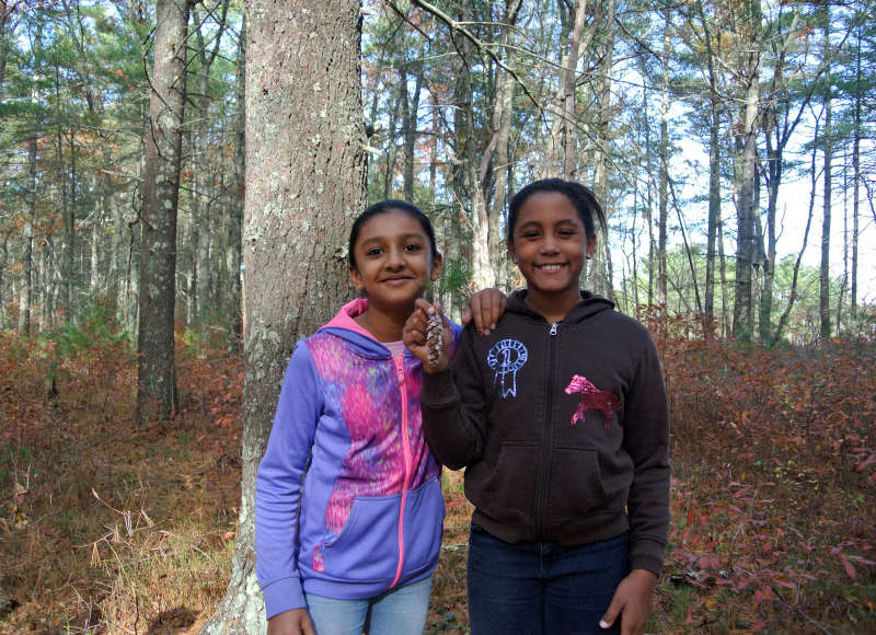 two girls holding a pine cone in William Minot Forest