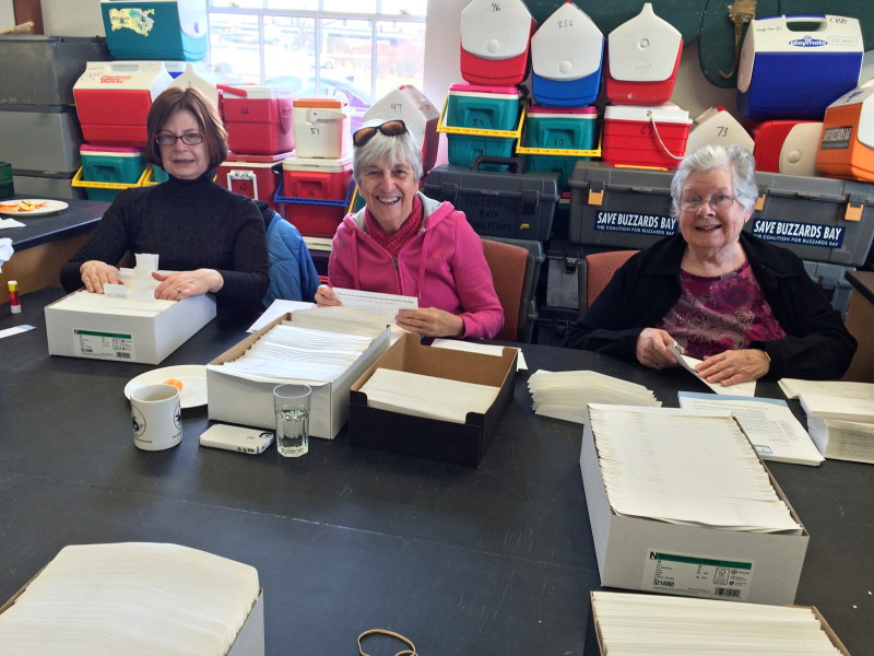 three women volunteering to stuff envelopes for the Buzzards Bay Coalition