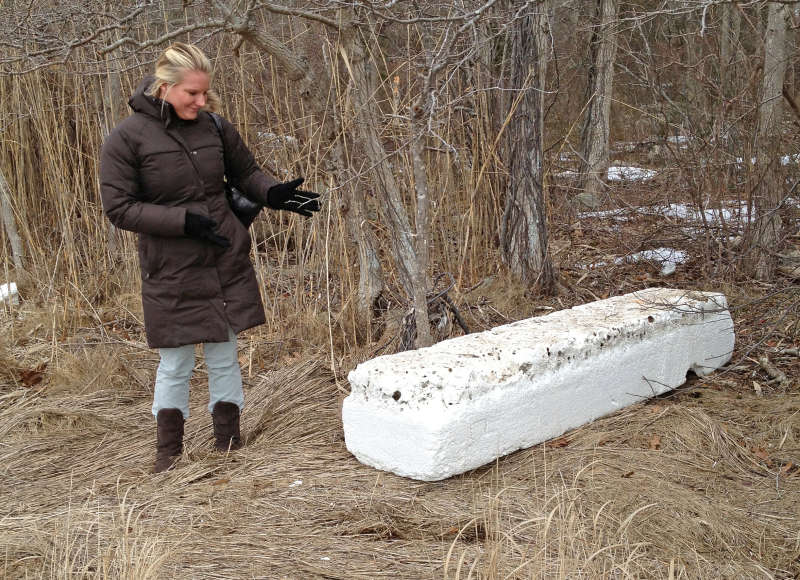 woman stands next to large foam block in a salt marsh in Mattapoisett