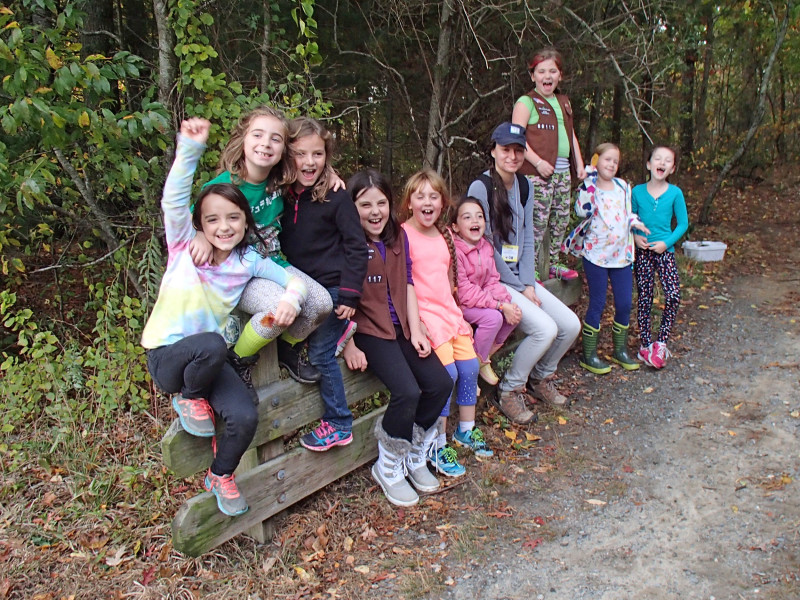 a group of Brownie scouts sitting on a log at Four Ponds Conservation Area in Bourne