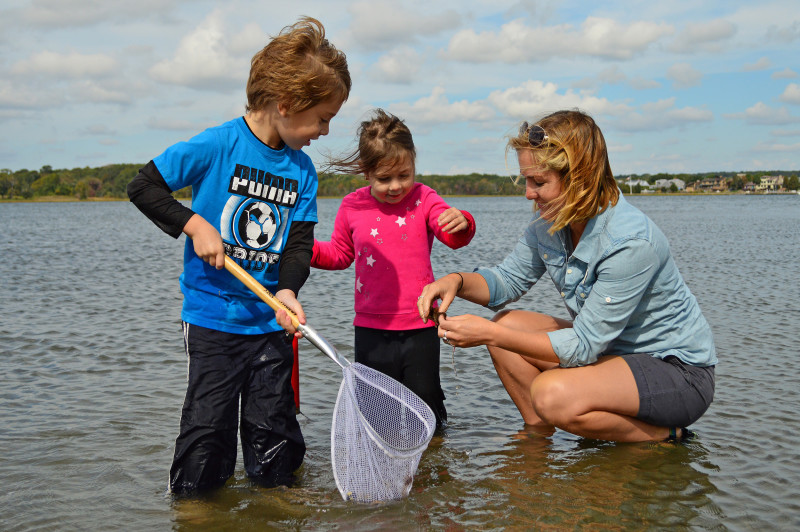 two kids and a woman wading in the water at Apponagansett Park in Padanaram