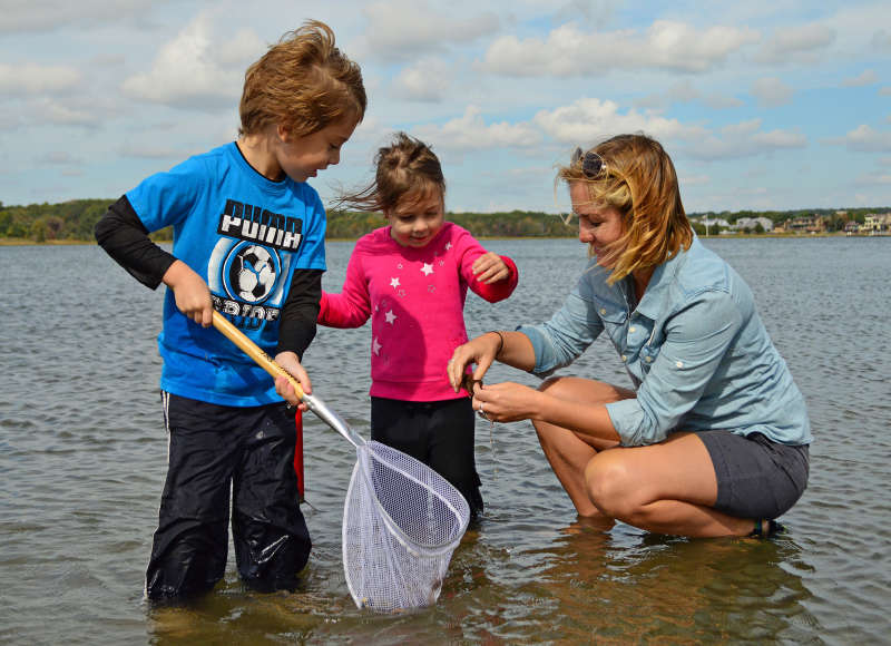 two kids and a woman wading in the water at Apponagansett Park in Padanaram