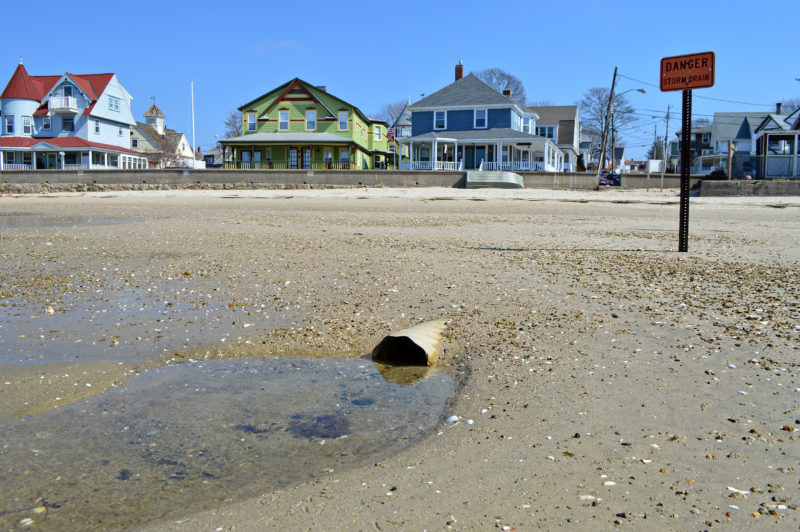 a storm drain and danger sign at a beach in Onset