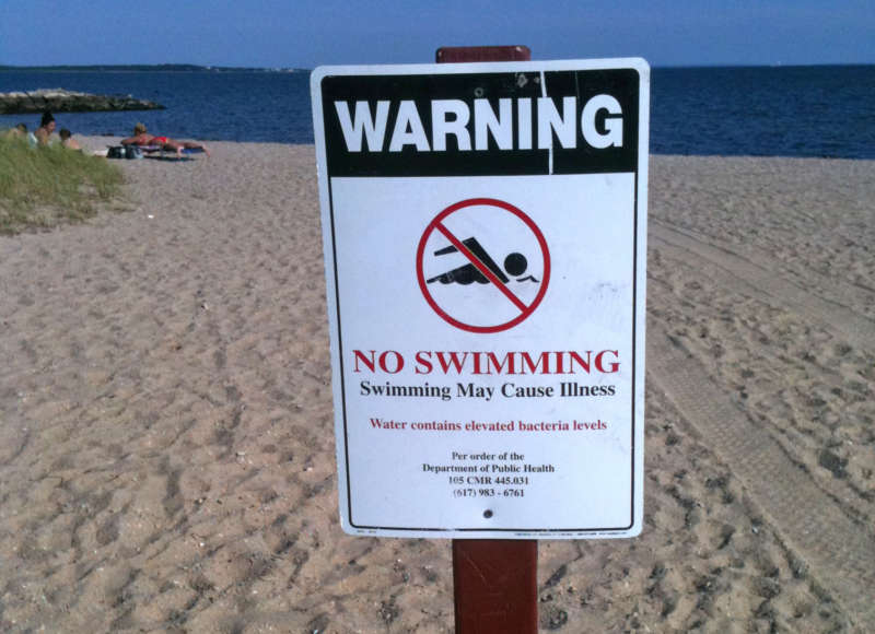 a no swimming sign posted at a beach on Buzzards Bay