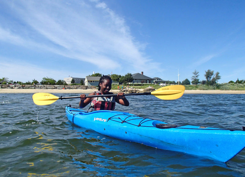 a girl kayaking off the coast of Fort Taber Park in New Bedford Harbor