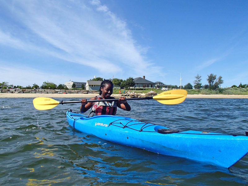 a girl kayaking off the coast of Fort Taber Park in New Bedford Harbor