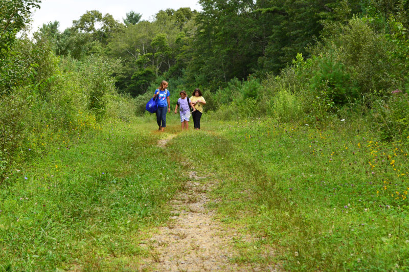 a woman and two girls walking on a path through the woods at Nasketucket Bay State Reservation