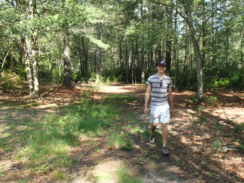 a man walks on a trail through the woods at Paskamansett Park in Dartmouth