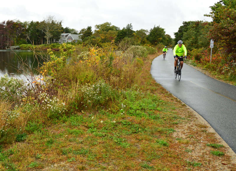 two cyclists ride past a pond on the Shining Sea Bikeway