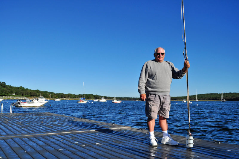 a volunteer Baywatcher holding a water sampling pole on a dock in Marion