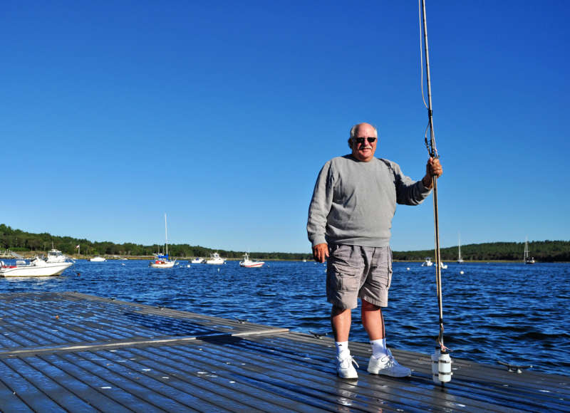 a volunteer Baywatcher holding a water sampling pole on a dock in Marion