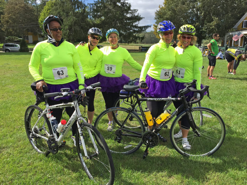 five women at a charity bike ride wearing purple tutus