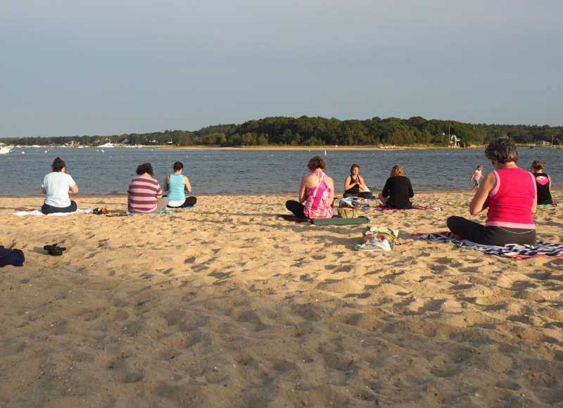 a group of people doing yoga on a beach