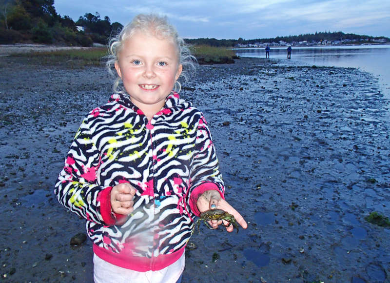 young girl holding a crab in a marsh