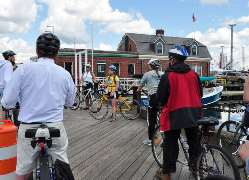 a group of bicyclists in downtown New Bedford next to the harbor
