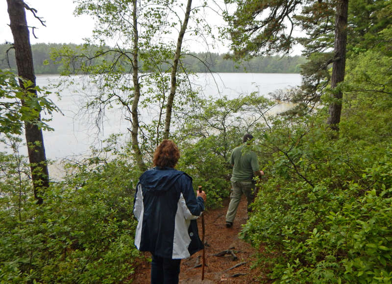 people walking on a trail by a kettle pond at Myles Standish State Forest