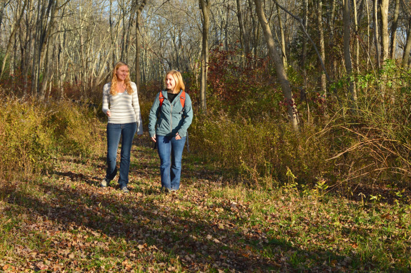 two young women walking through the woods at The Sawmill in Acushnet