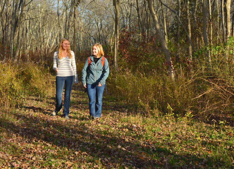 two young women walking through the woods at The Sawmill in Acushnet