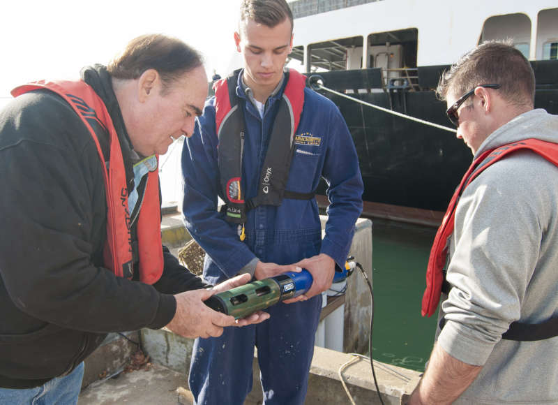 Massachusetts Maritime Academy professor and students standing by the water holding a sonde