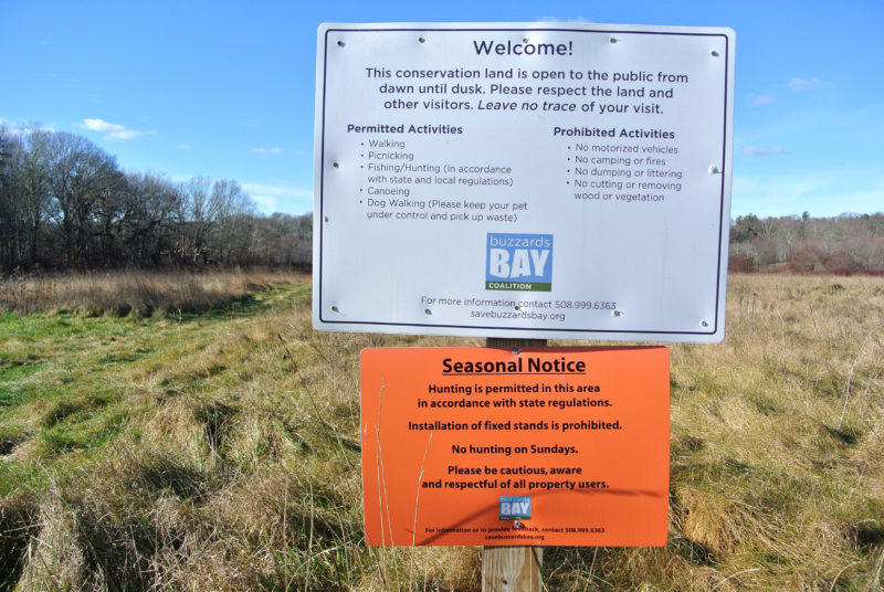 a sign stating that hunting is allowed at the entrance to a Buzzards Bay Coalition conservation property in Massachusetts